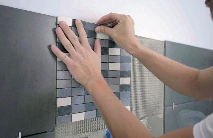 Person bringt Mosaikfliesen an